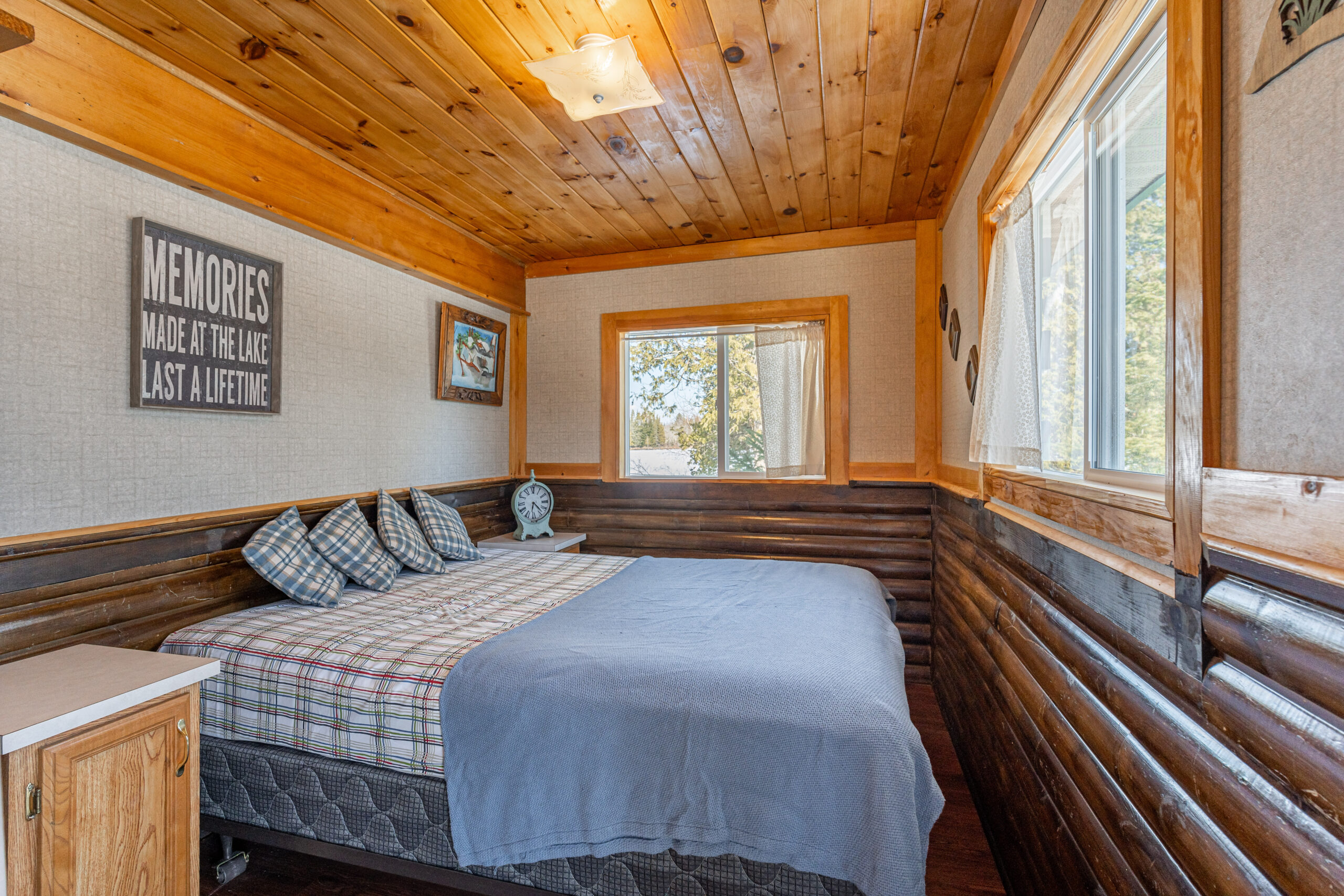 A bed with a checkered cover and light blue throw blanket