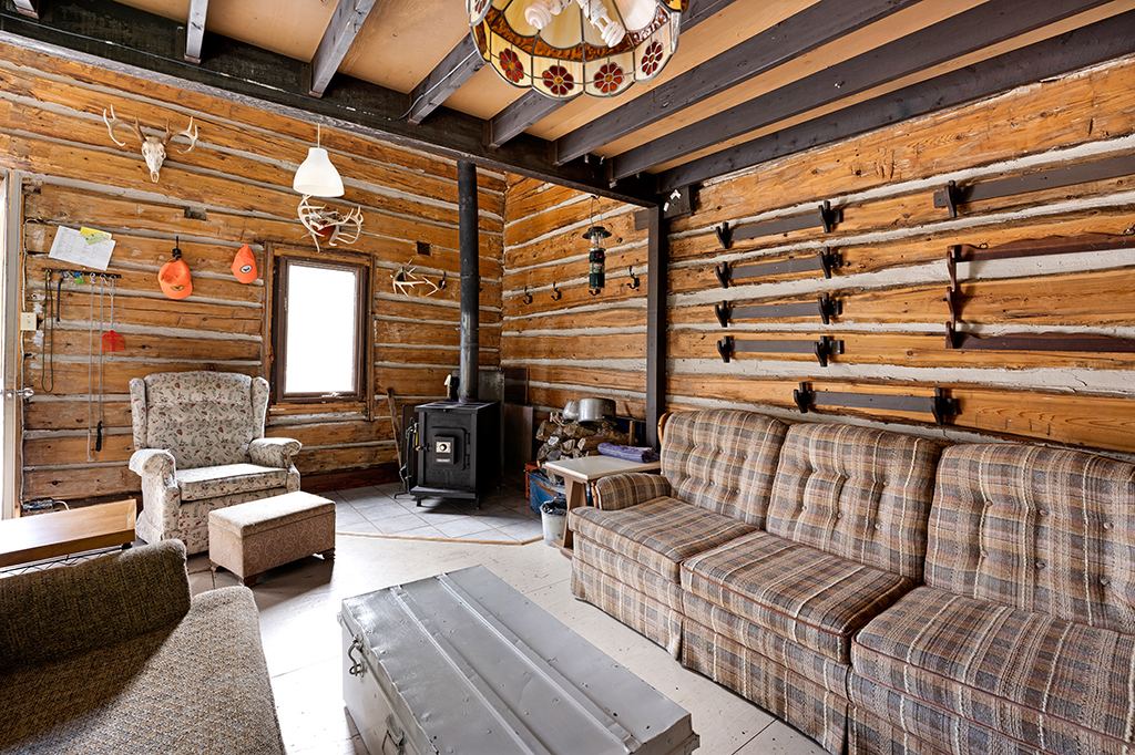 A plaid couch next to a wood stove in a wood-paneled room