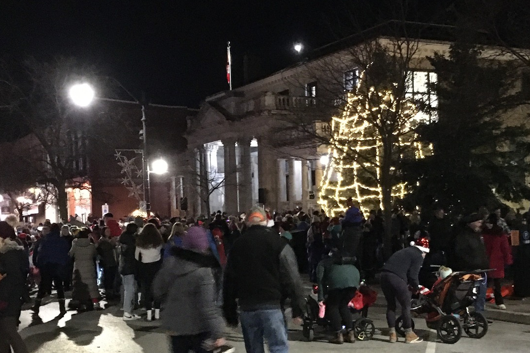 a lit-up christmas tree with folks gathered around