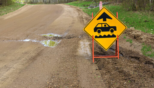 A bumpy road ahead sign with a large pothole