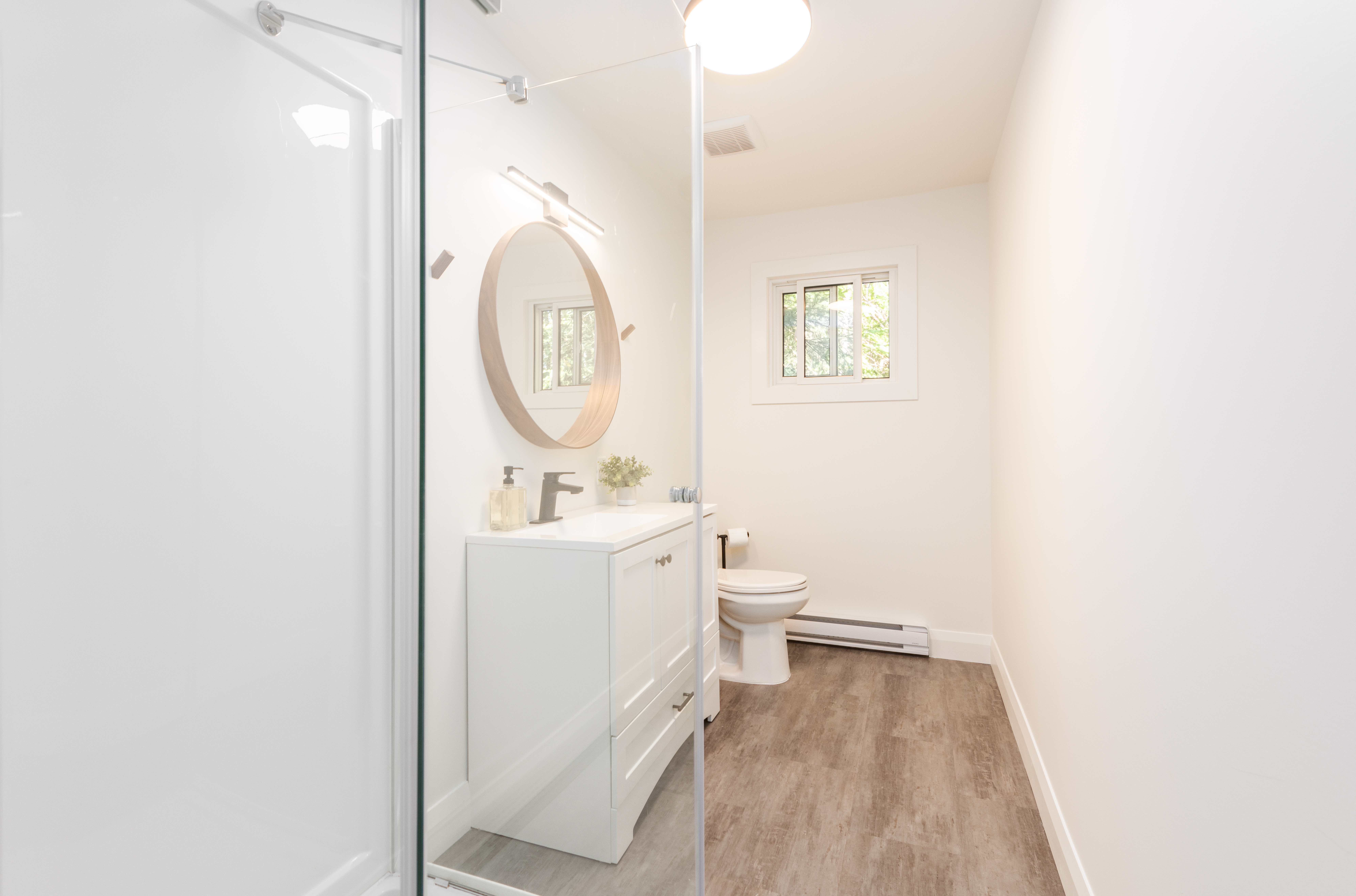 A white bathroom with light wood floors