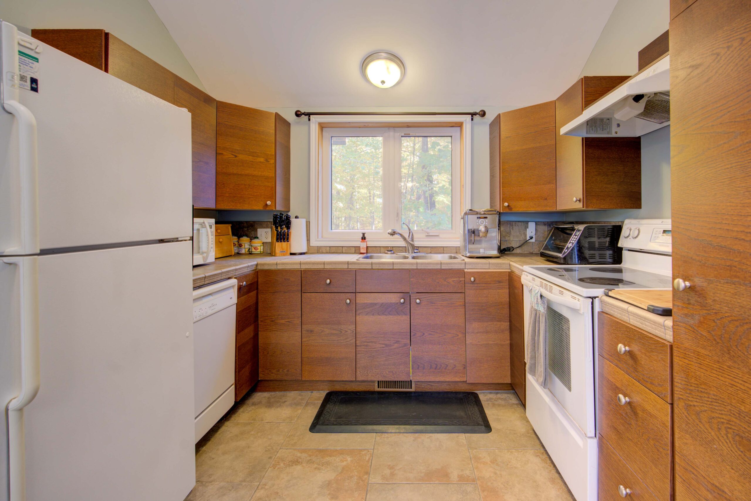A kitchen with brown wood cabinets and white appliances