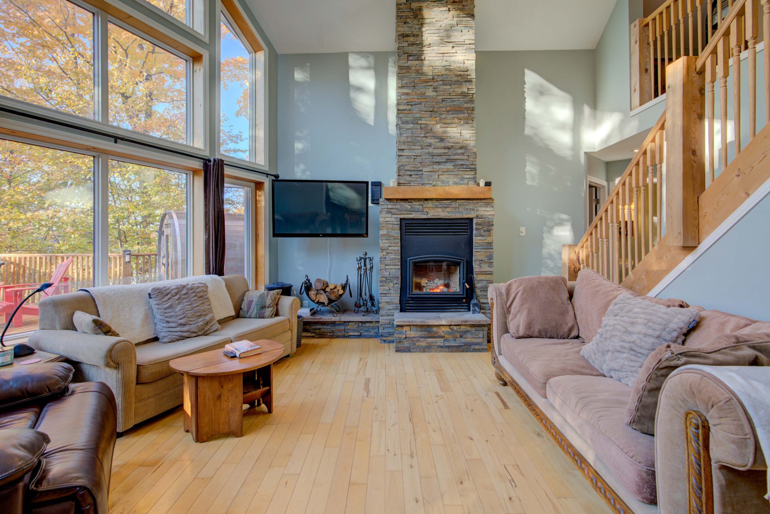 Couches face each other in a large living area with vaulted ceilings. A stone fireplace is on the far wall