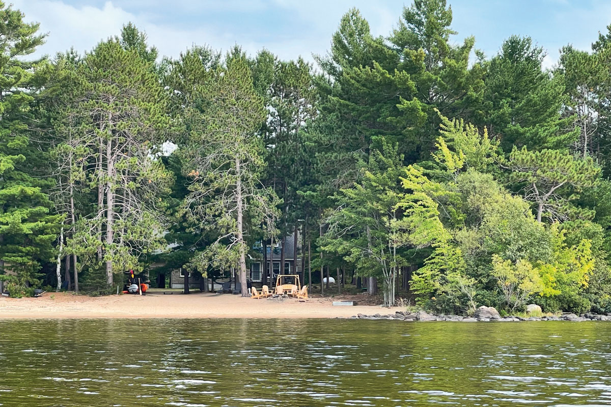 a photo of a waterfront with green trees and a sandy beach