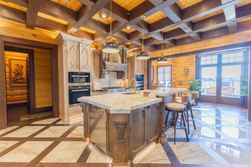 A large kitchen with birch-toned cabinets and white marble countertops. White tiled floors have a brown criss-cross pattern.