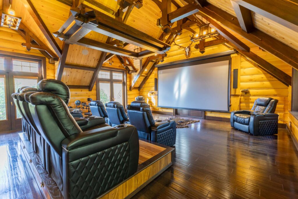 Black recliner chairs face a movie face