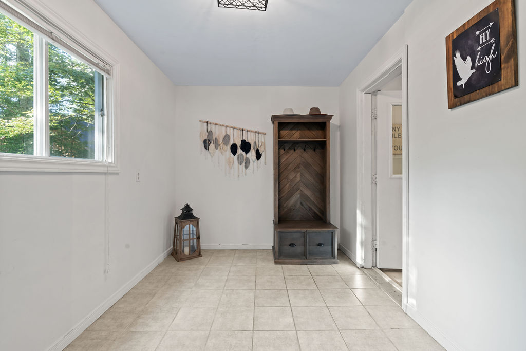 A small mudroom storage unit and a hanging rack in an empty white room