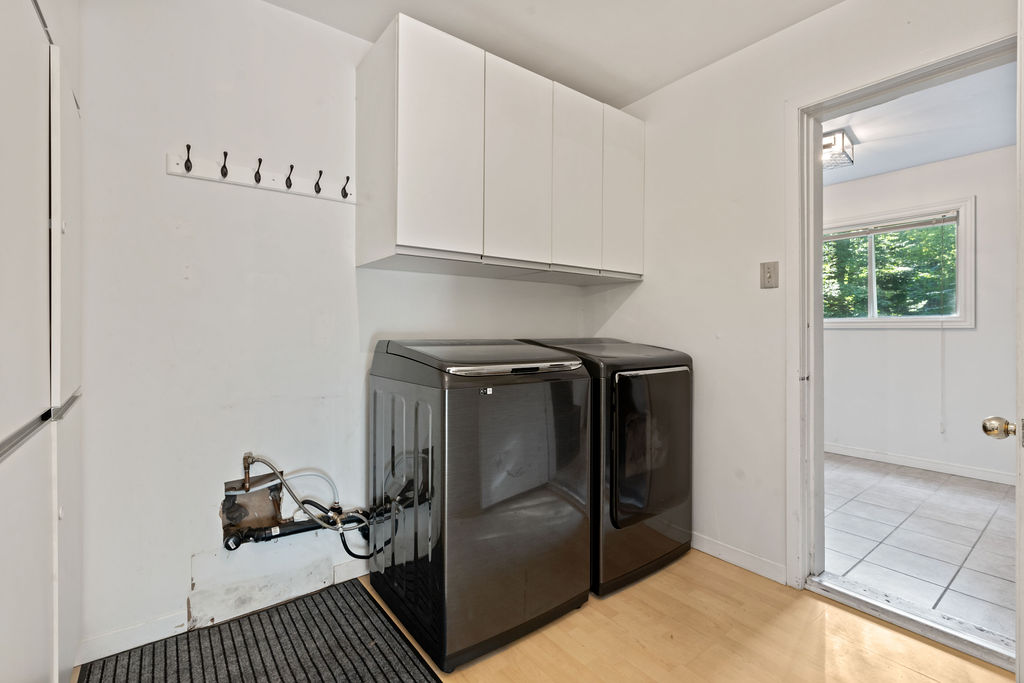Dark grey laundry machines sit next to each other on light wood floors