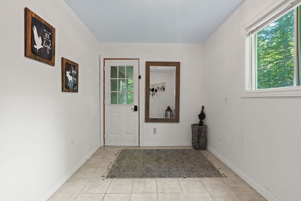 A white entryway with a small carpet and a mirror