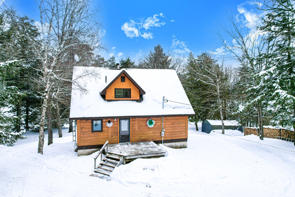 A red-brown cottage with black trim in the snow