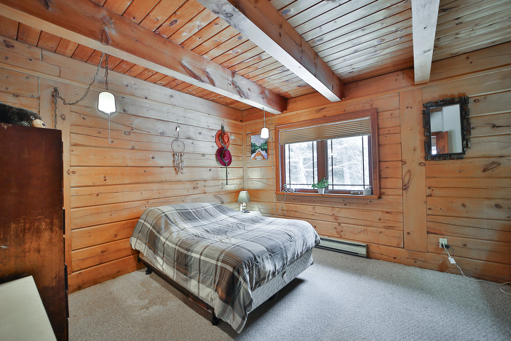 A black-and-white plaid bed in a wood-paneled room
