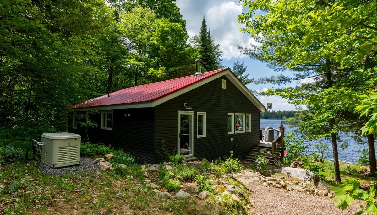 A grey paneled cottage with a red roof