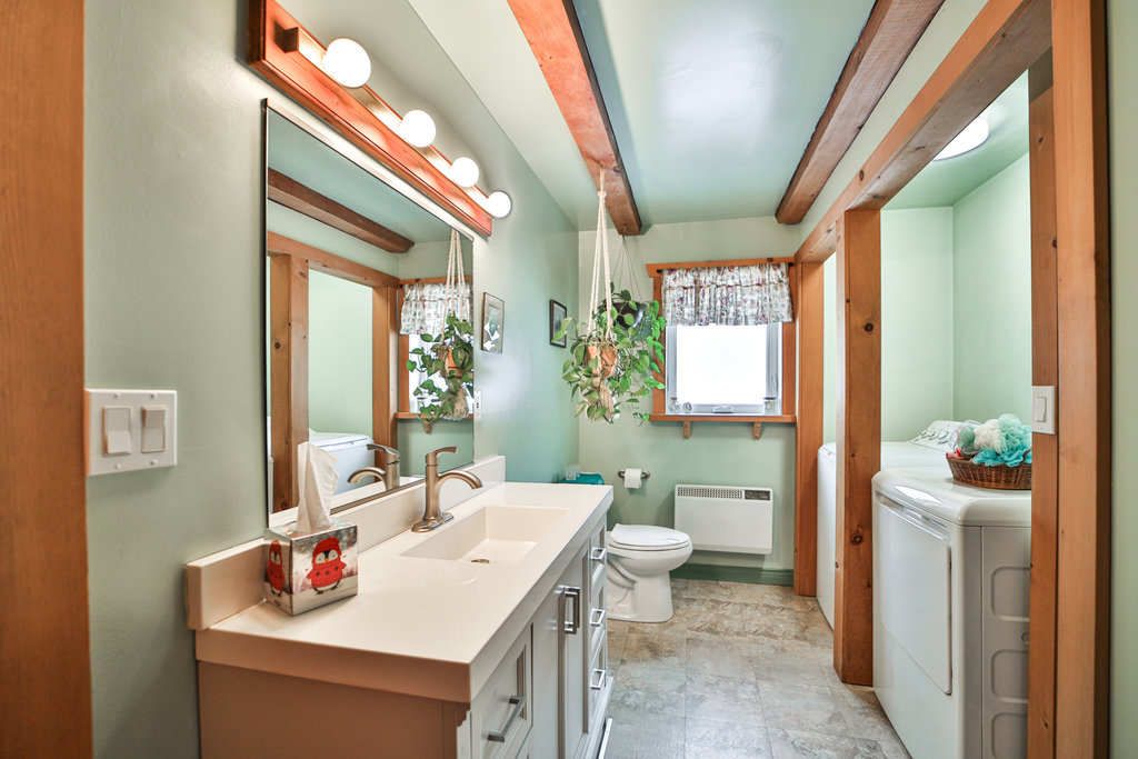 A wood vanity with a mirror hanging above in a light teal bathroom