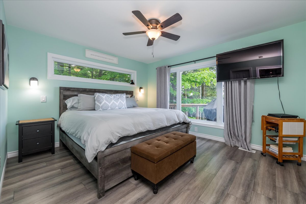 A large white bed on a grey bed frame in a teal room
