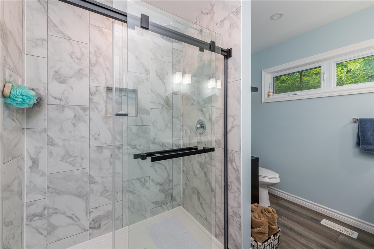 A glass shower with marbled walls