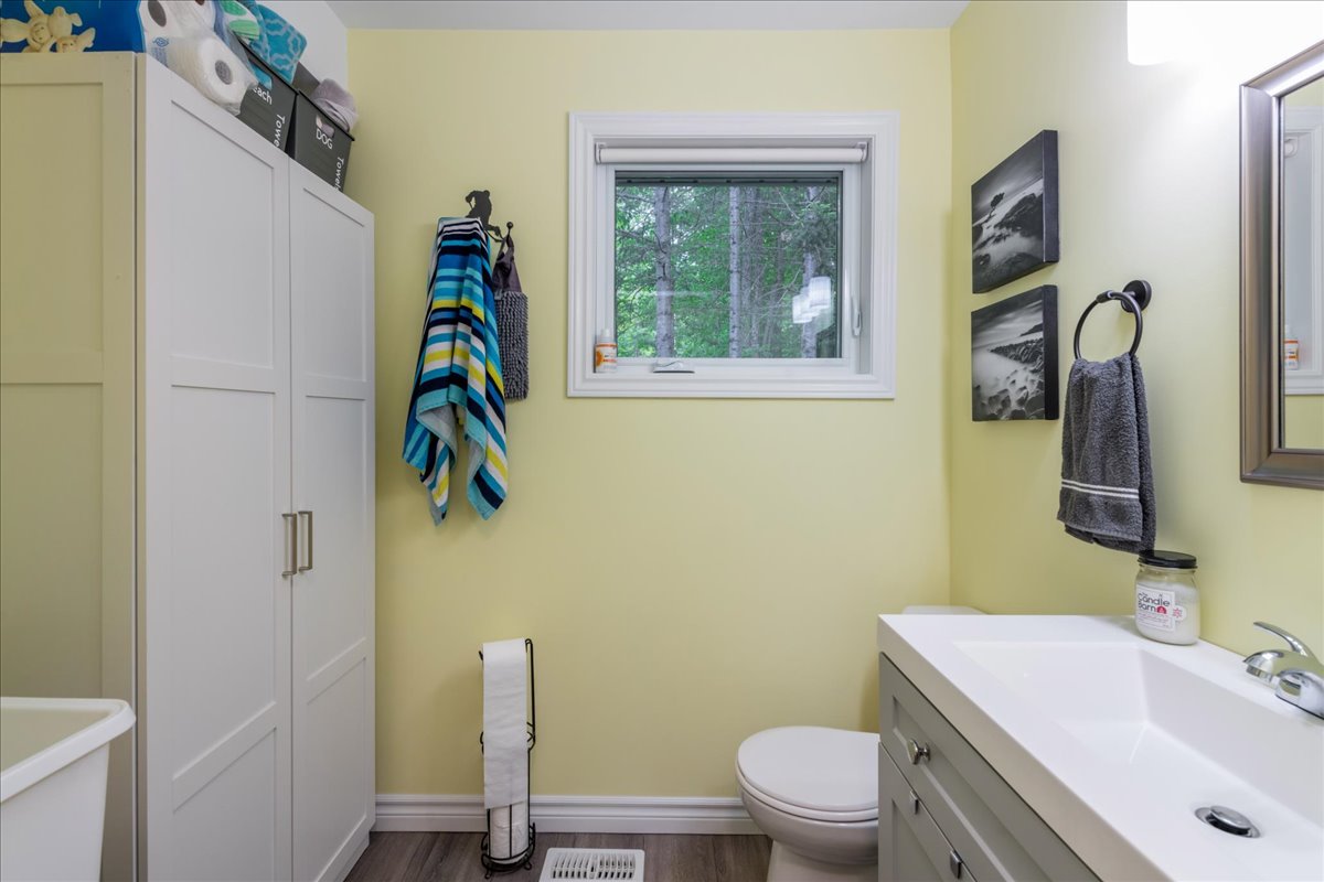 A toilet faces a wall of white cabinets in a yellow bathroom