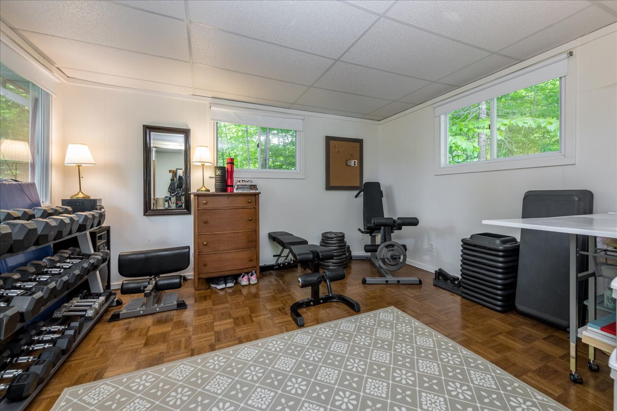 A white room with brown wood floors and weight lifting equipment