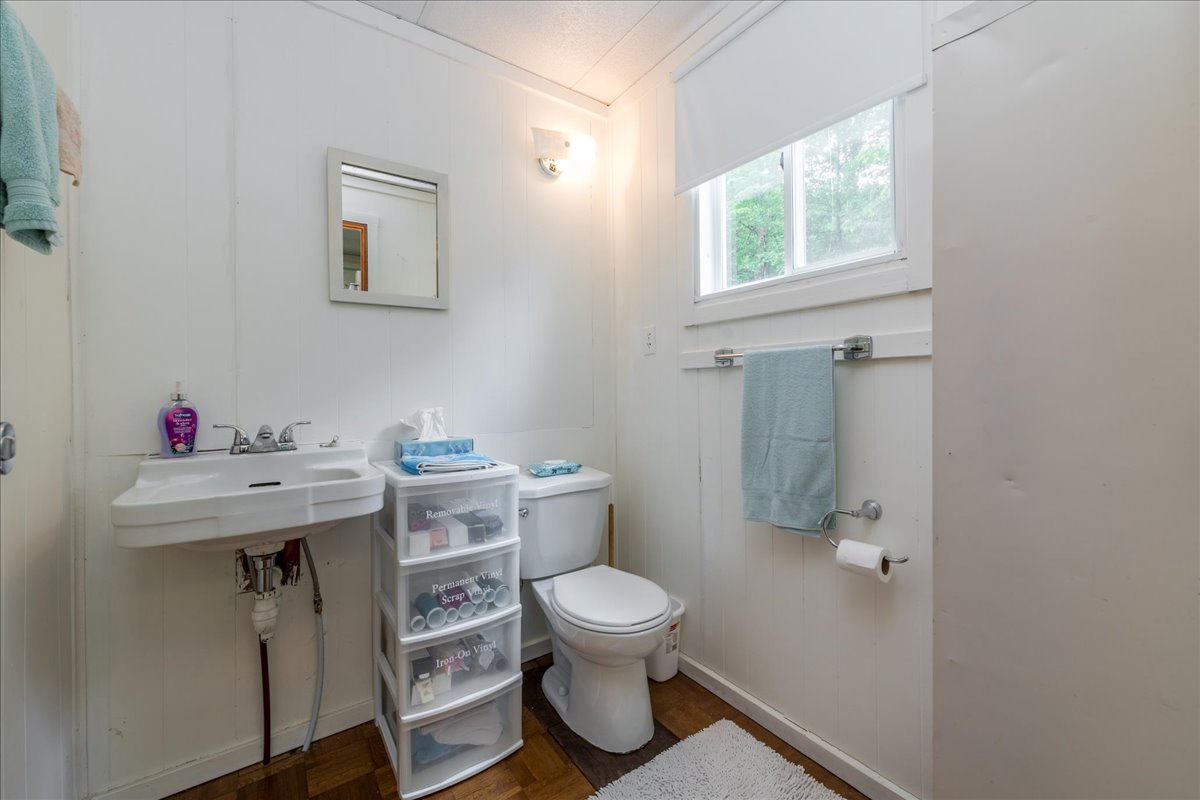 A white bathroom with plastic drawers beside the toilet