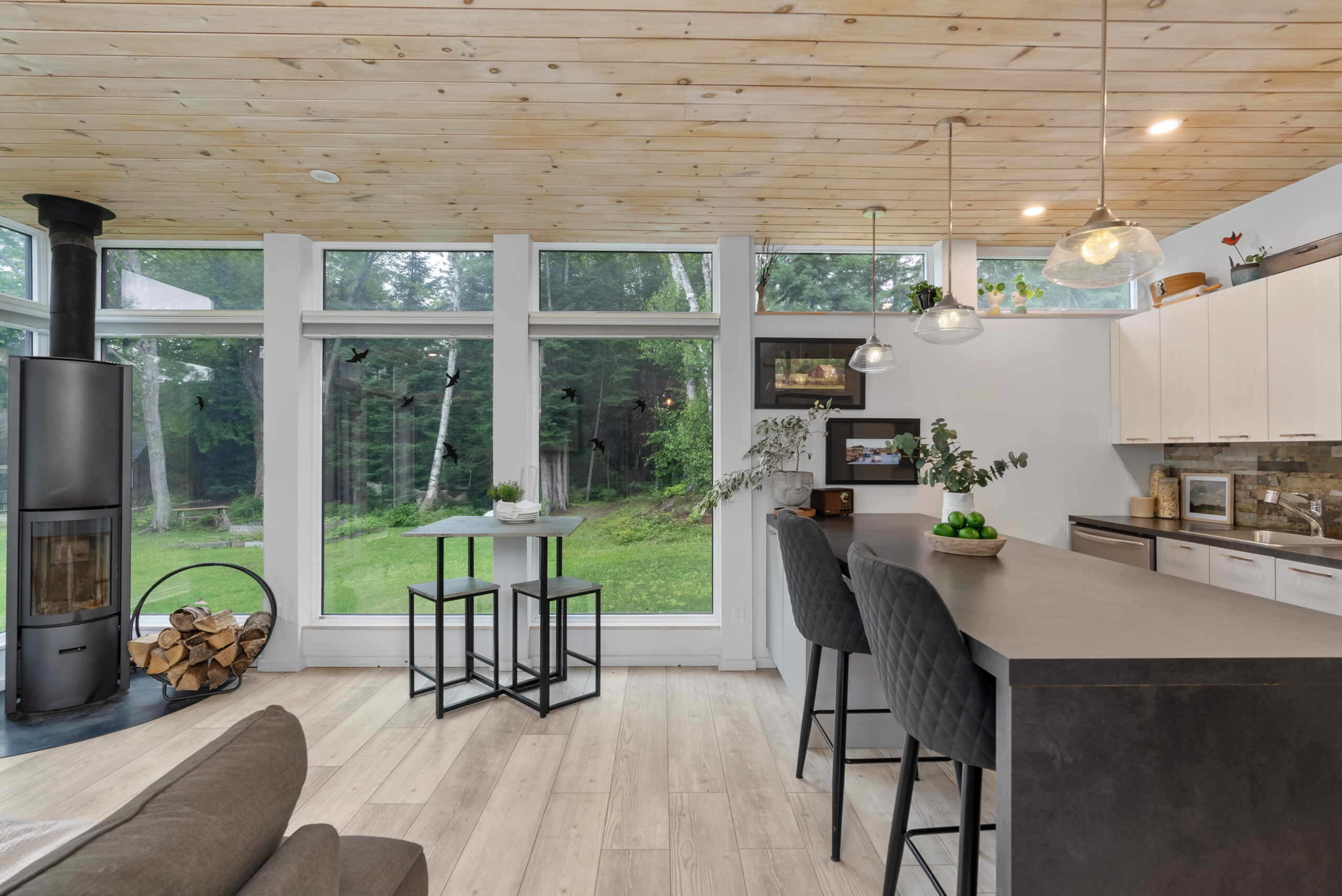 A small hightop seating area next to a breakfast countertop in a glass room
