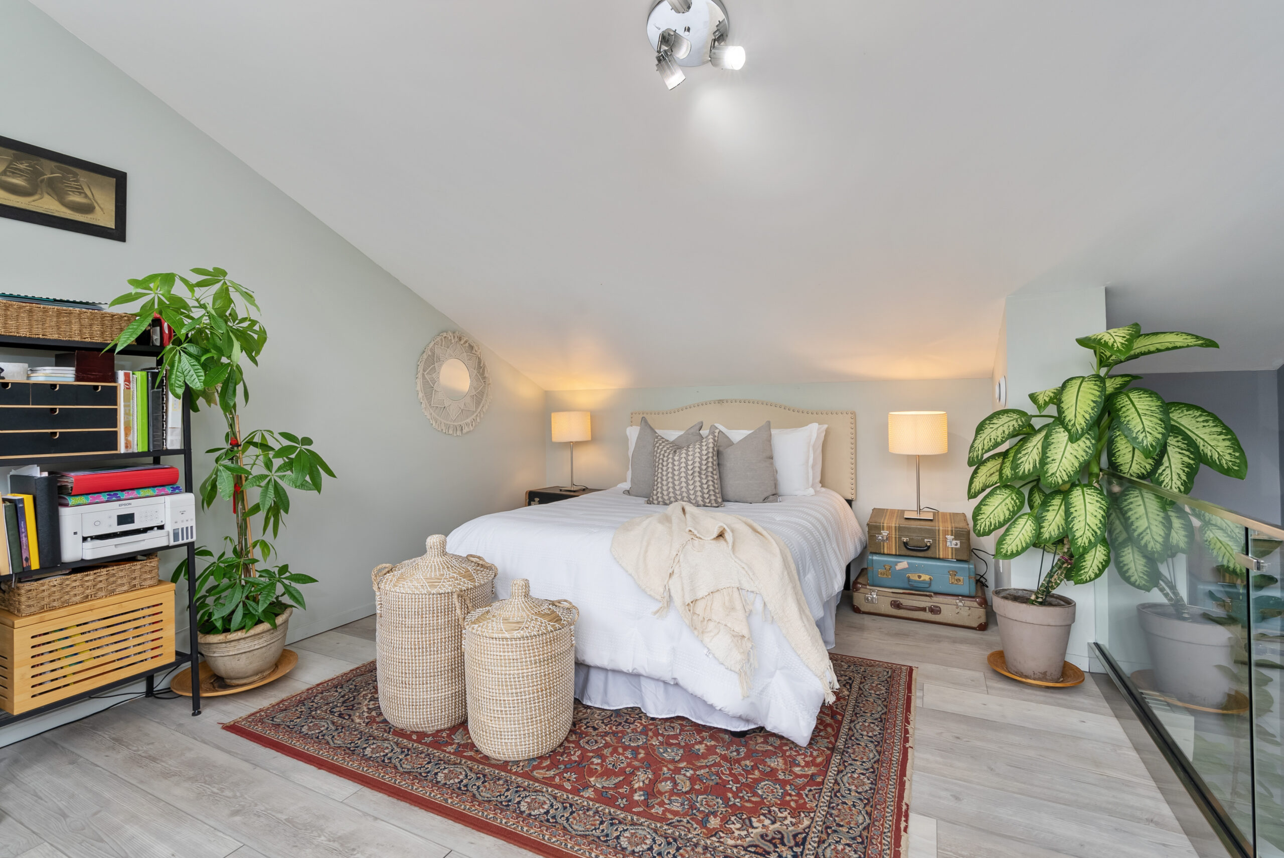 A white bed on a red patterned carpet in a white room