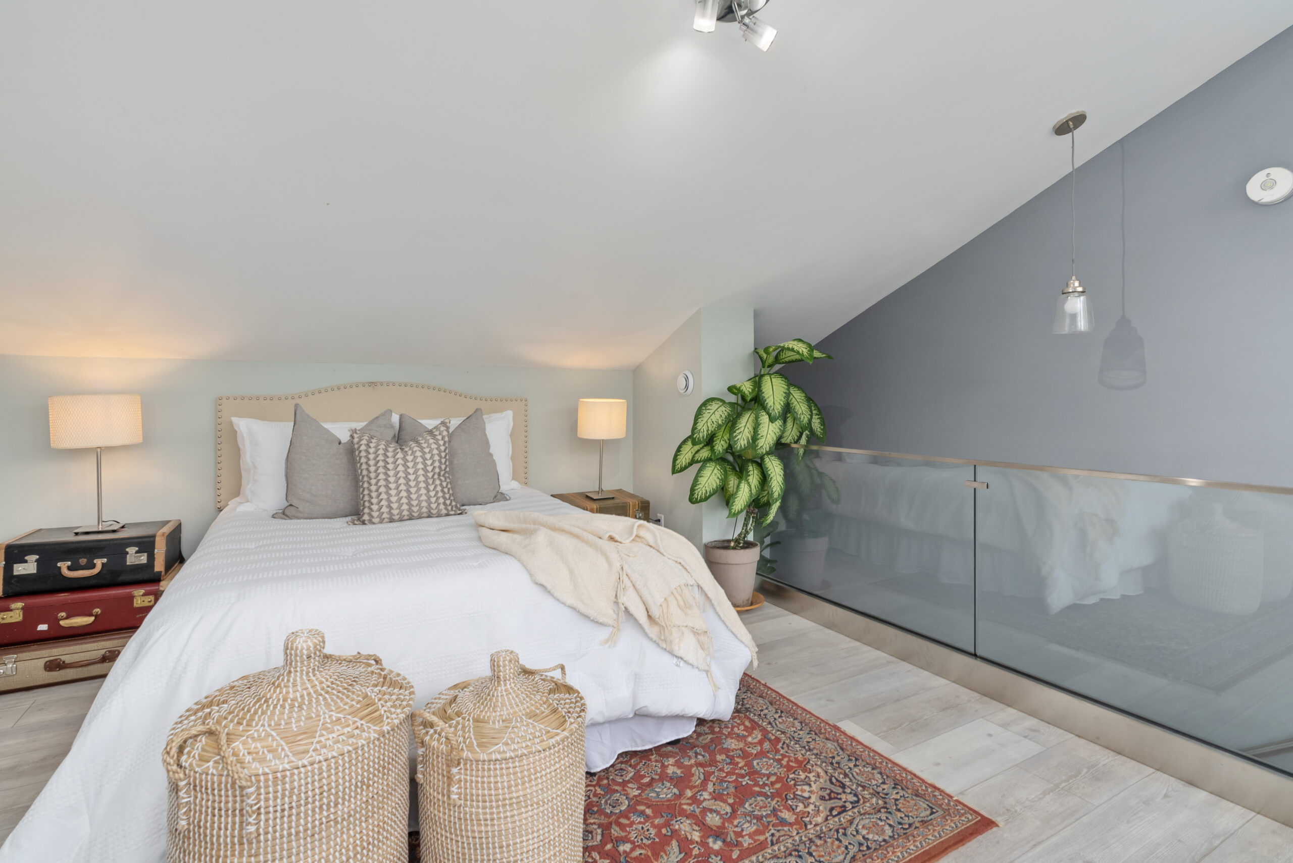 A white bed on a red patterned carpet in a white room