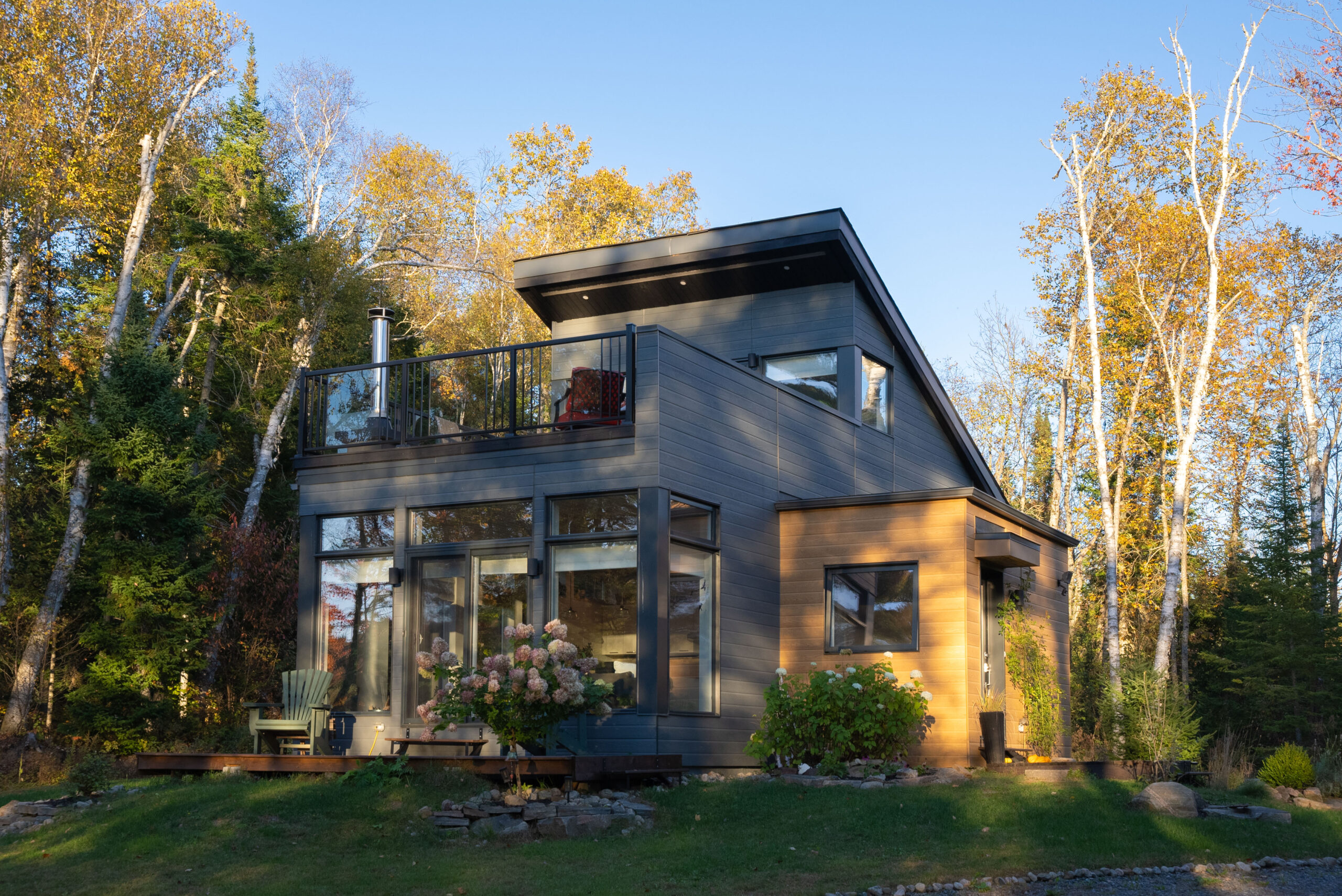 A two-story grey cottage with a lower level patio