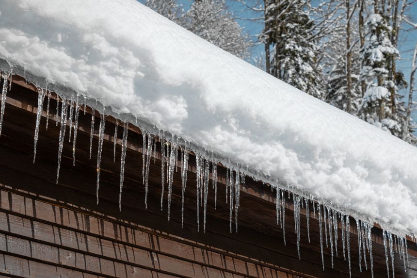 A snow covered roof with icicles