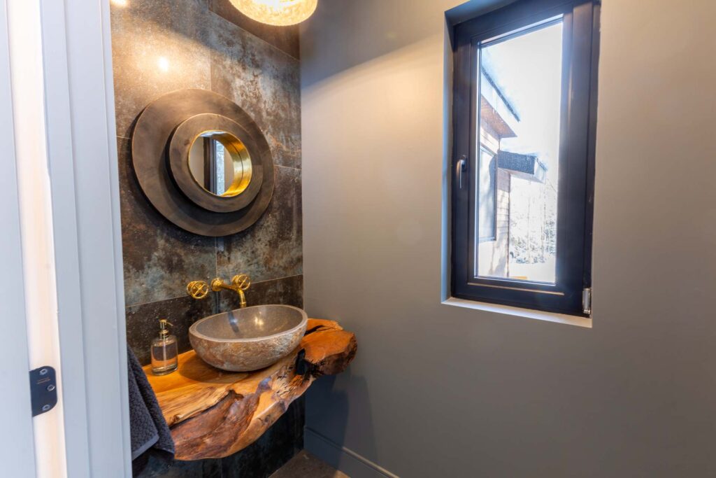 A bowl sink on a wood vanity with a round mirror
