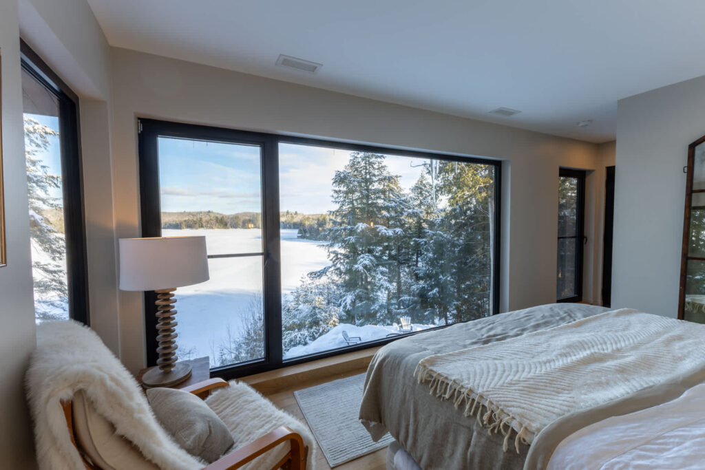 A white bed faces a floor-to-ceiling windows
