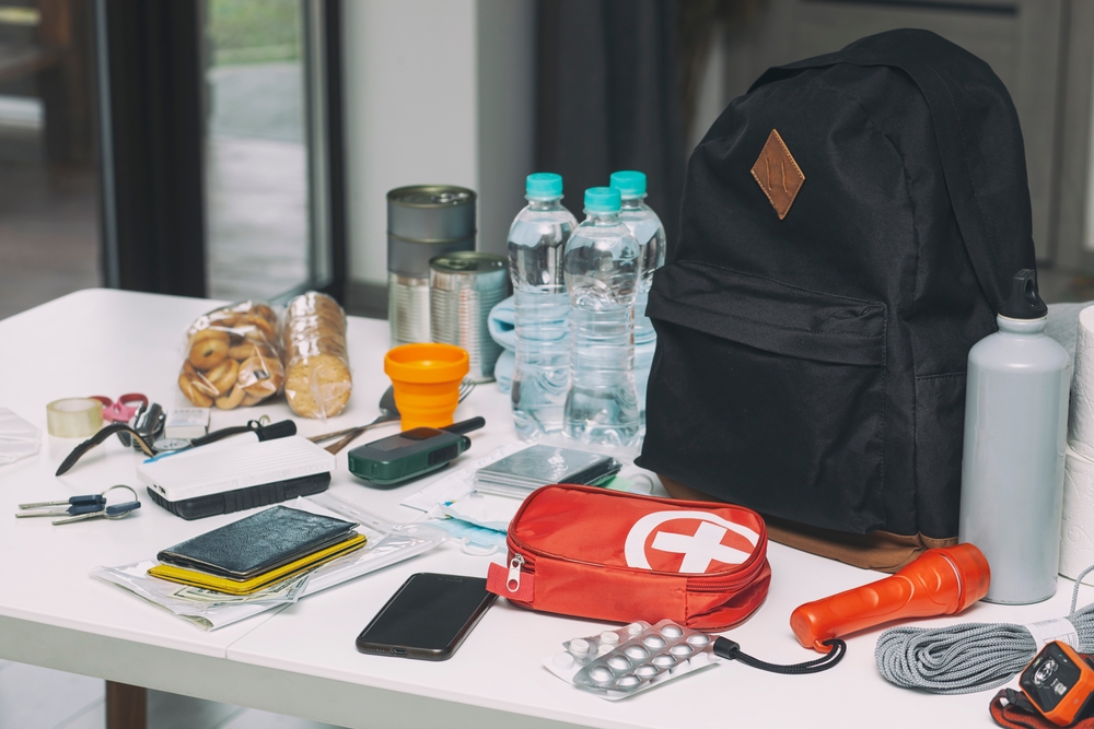 Emergency kit organized on the table. Documents, water, food, first aid kit and another items needed to survive.