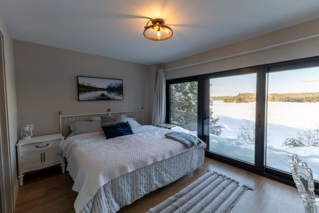 A large white bed next to floor-to-ceiling windows