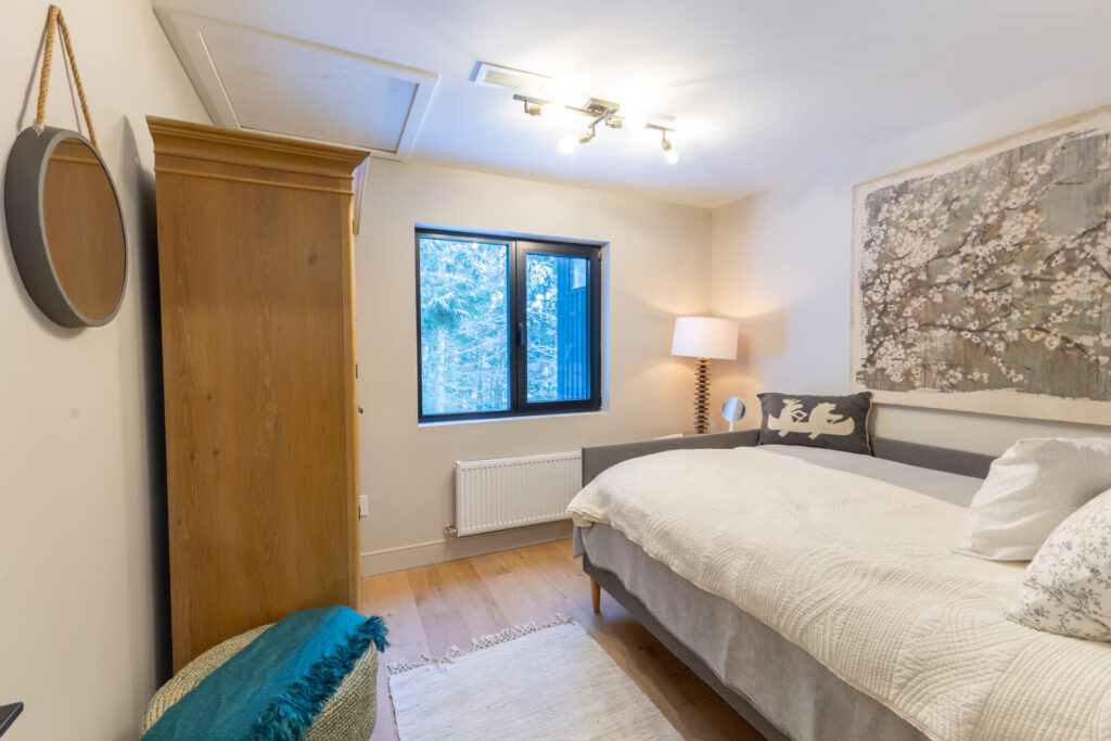 A grey bed frame with a white bed in a small bedroom