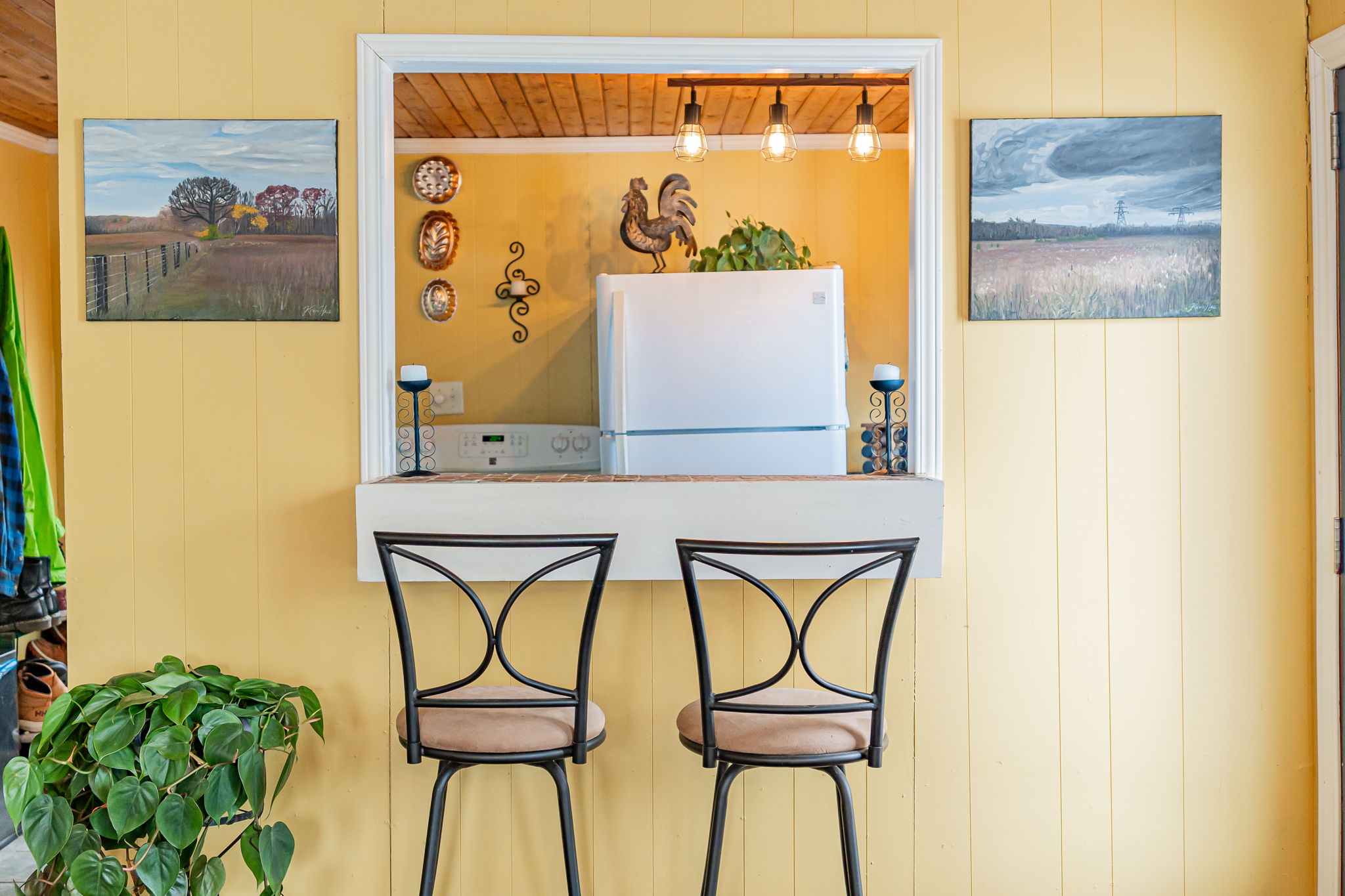 Two high-top chairs are tucked under a kitchen pass-through window