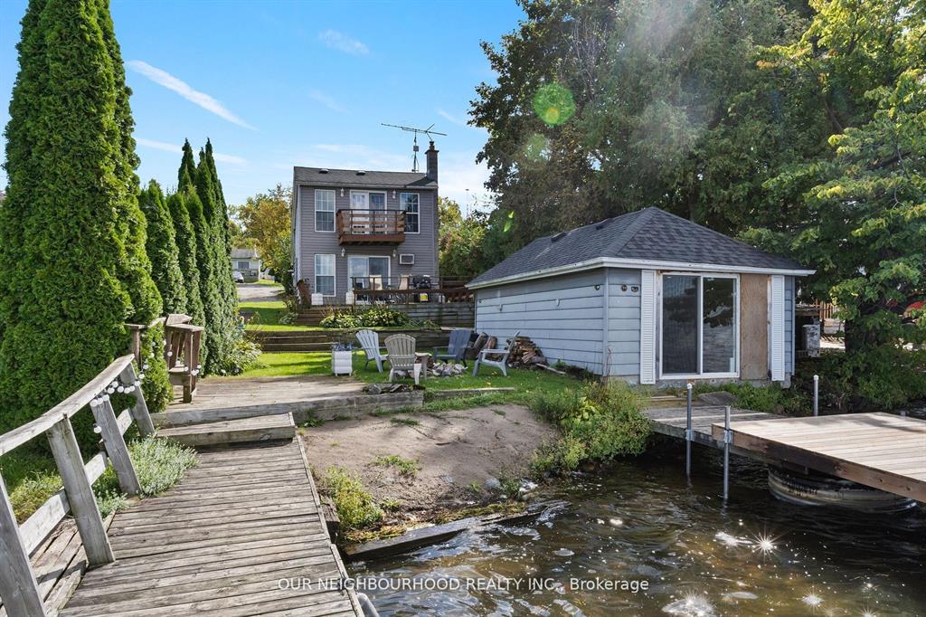 A small white bunkie next to a wood deck on the cottage property