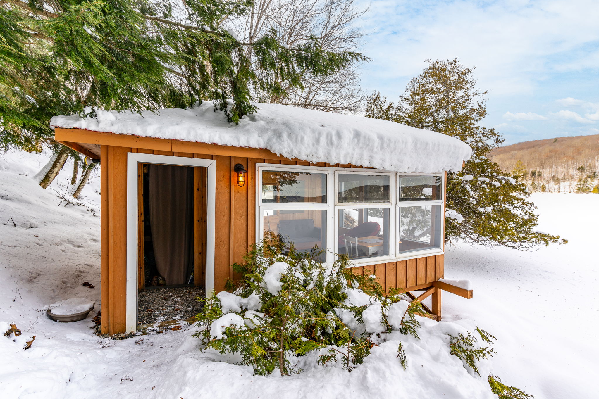 A wood bunkie with a covered glass porch