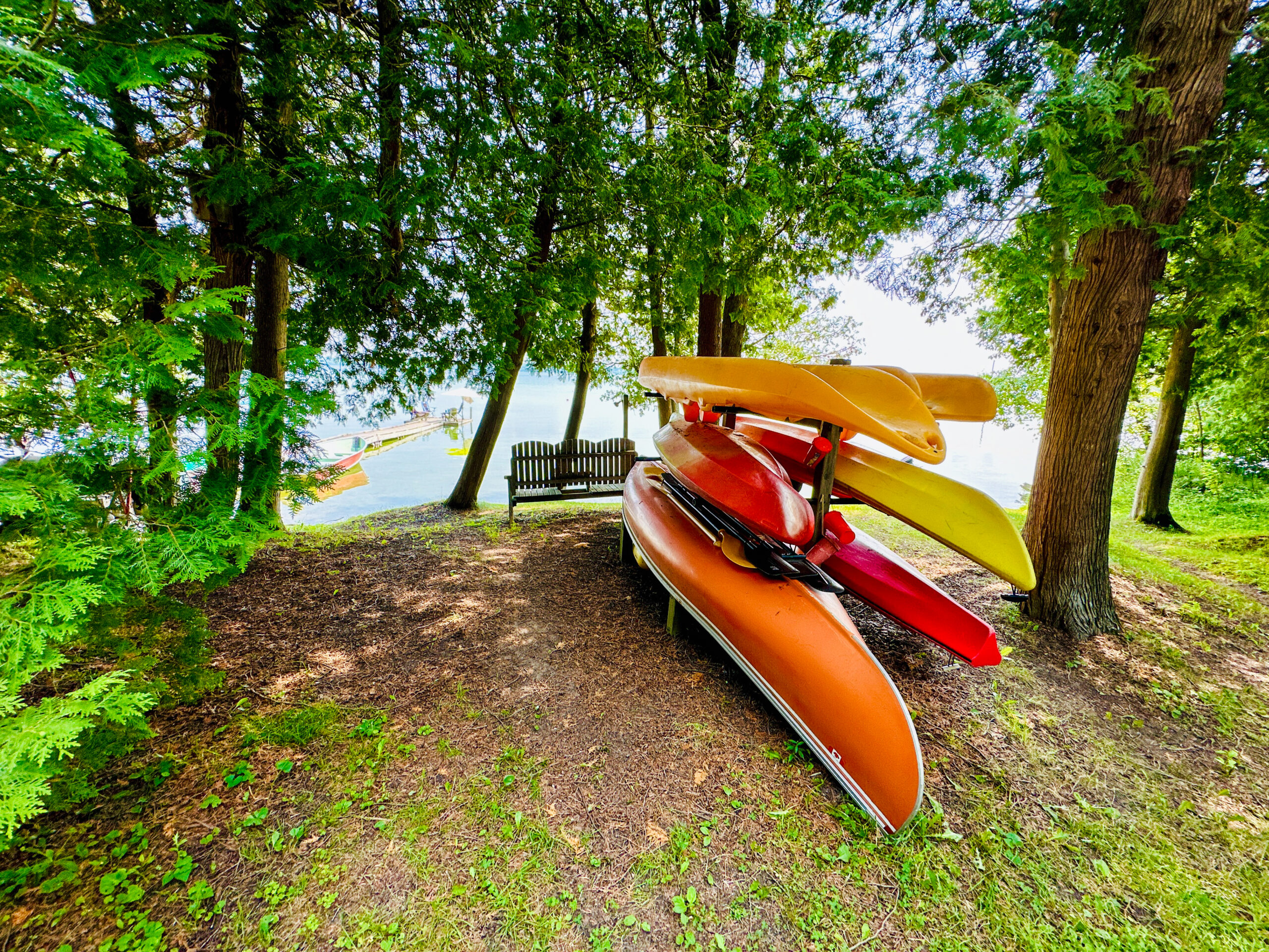 A lakeside canoe rack with colorful canoes ready for adventure on Lake Mindemoya.