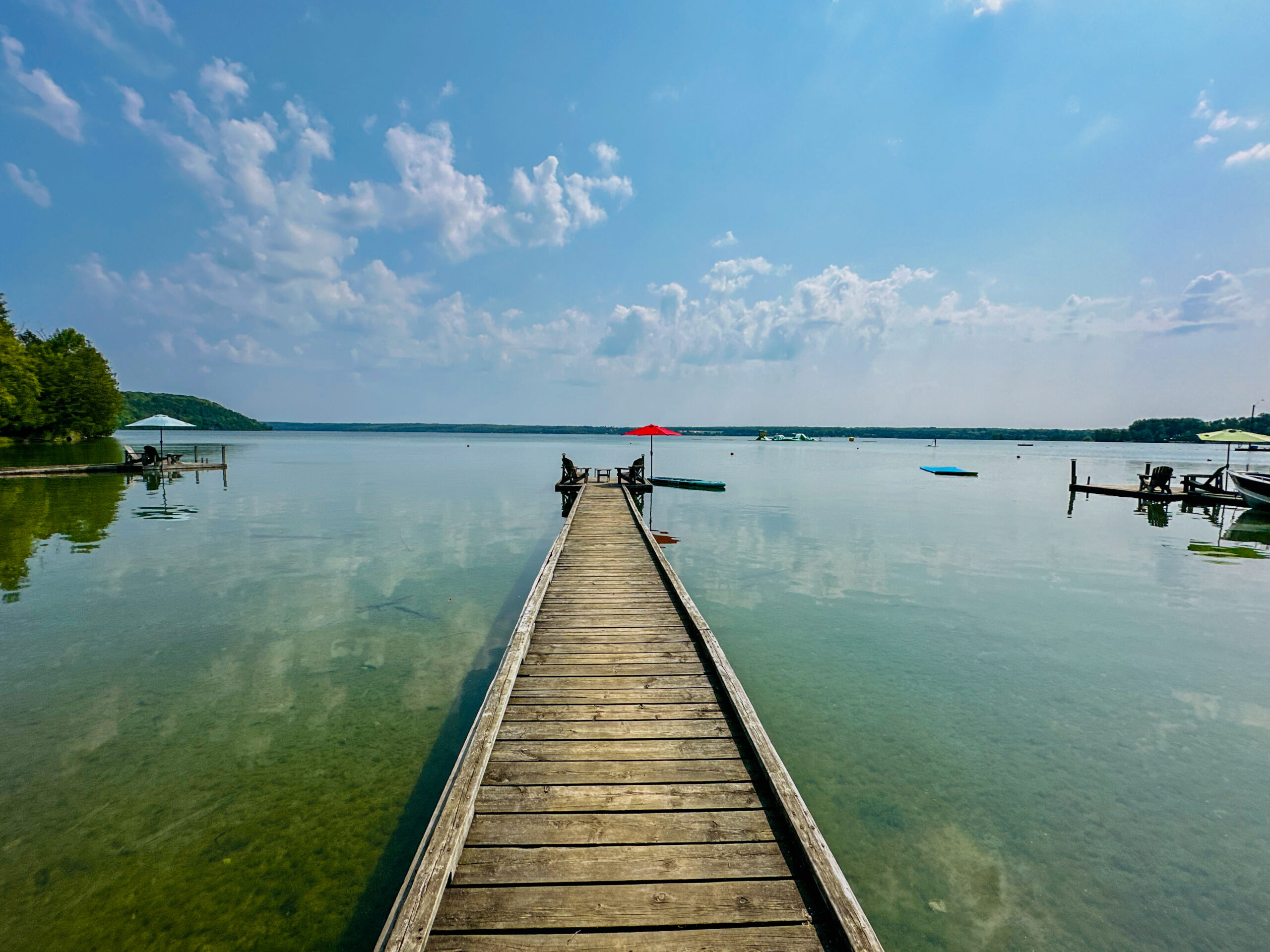 A wooden dock extending into the crystal-clear waters of Lake Mindemoya, offering direct lake access.