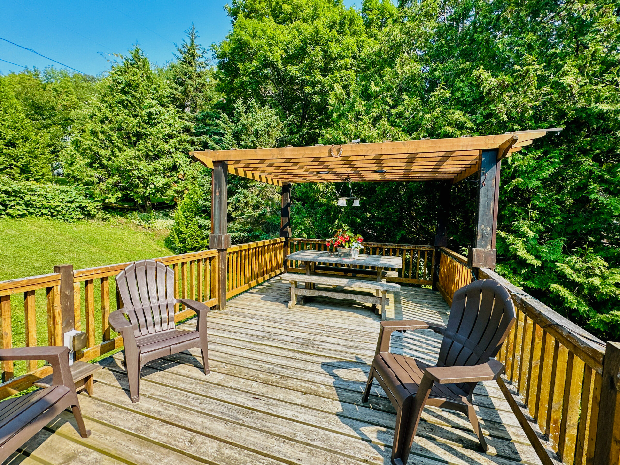A spacious outdoor pergola attached to the main house, offering shaded seating and stunning views.