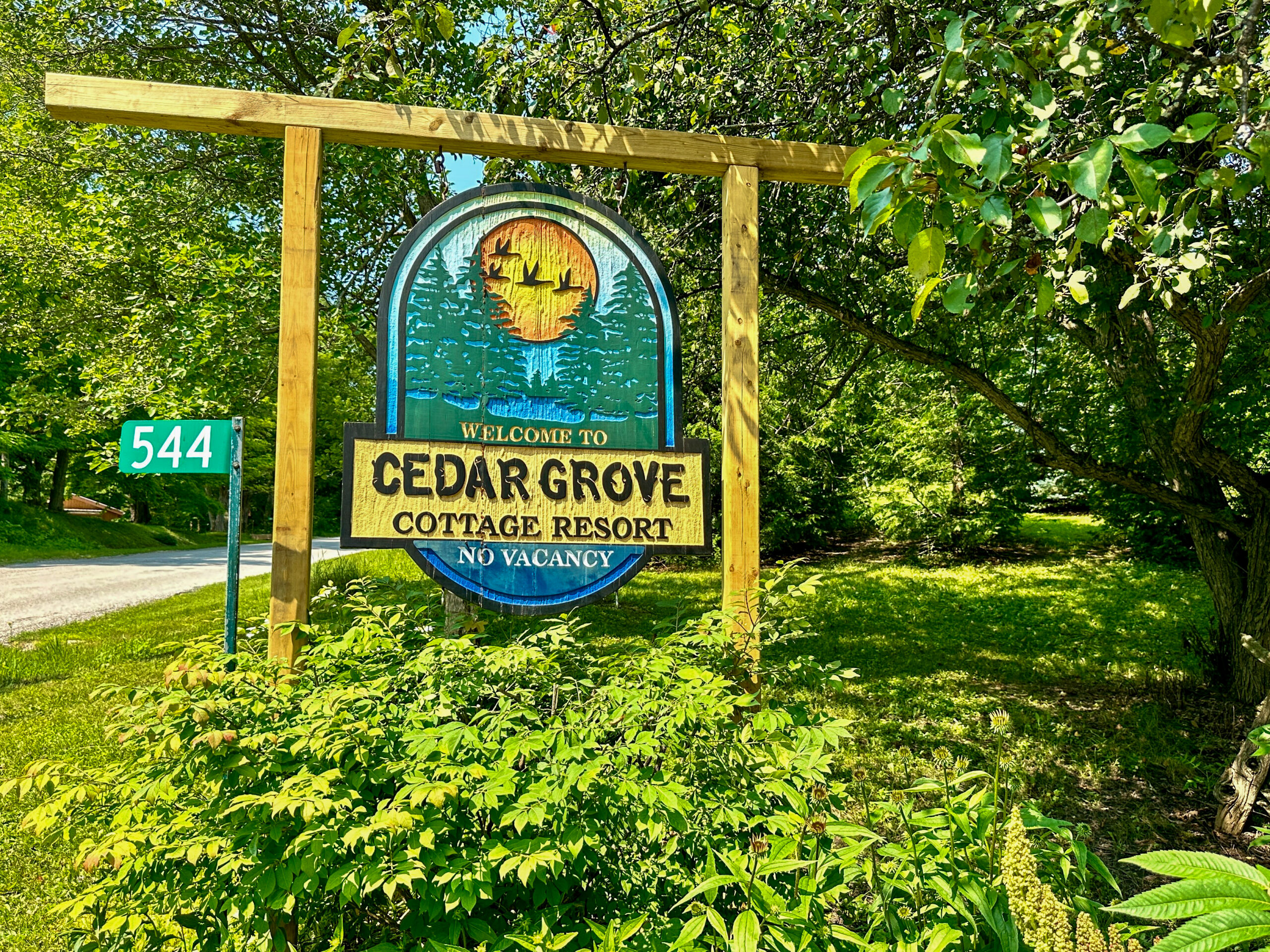 A welcoming wooden sign marking the entrance to Cedar Grove Cottages, a resort on Lake Mindemoya.