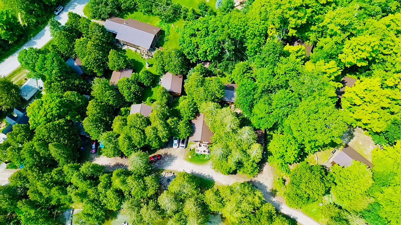 A top-down aerial shot showcasing the cabins, main house, and surrounding natural landscape.