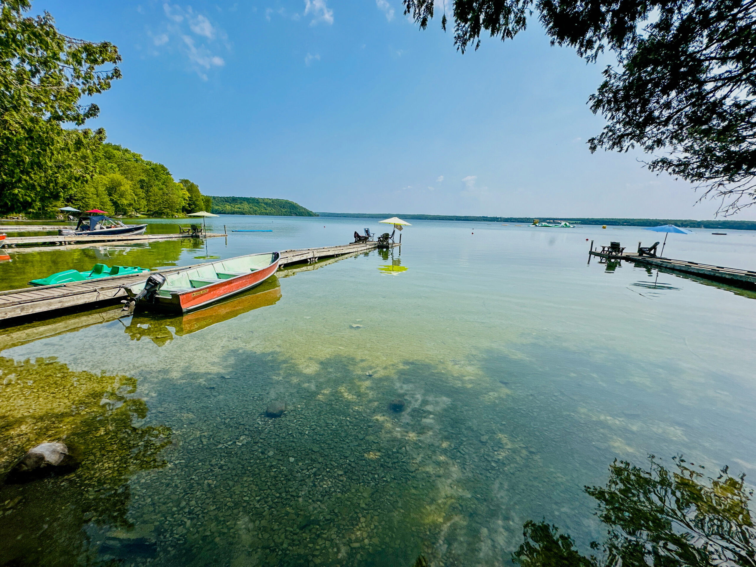 A peaceful waterfront scene showcasing Lake Mindemoya’s pristine shoreline and dock access.