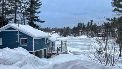 A snowy side entrance to a blue cottage