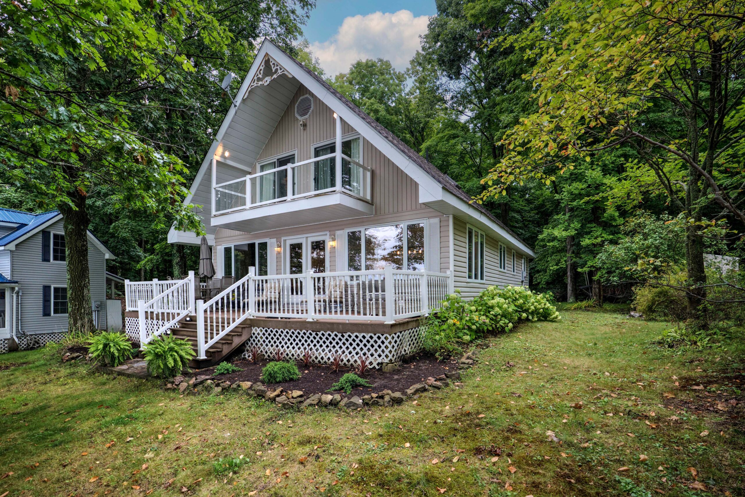A triangular beige paneled cottage on a grassy lawn