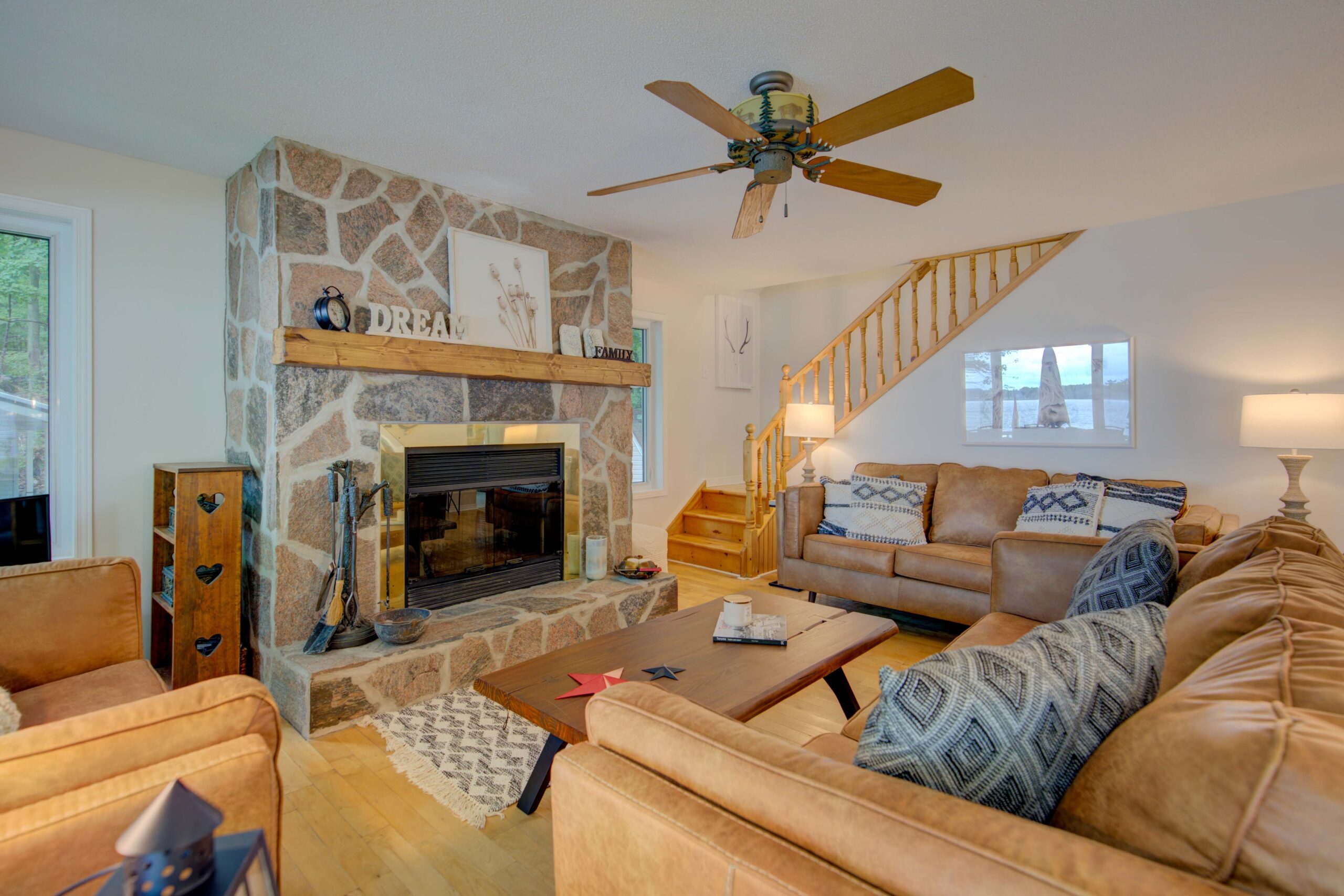 A brown suede couch faces a stone fireplace