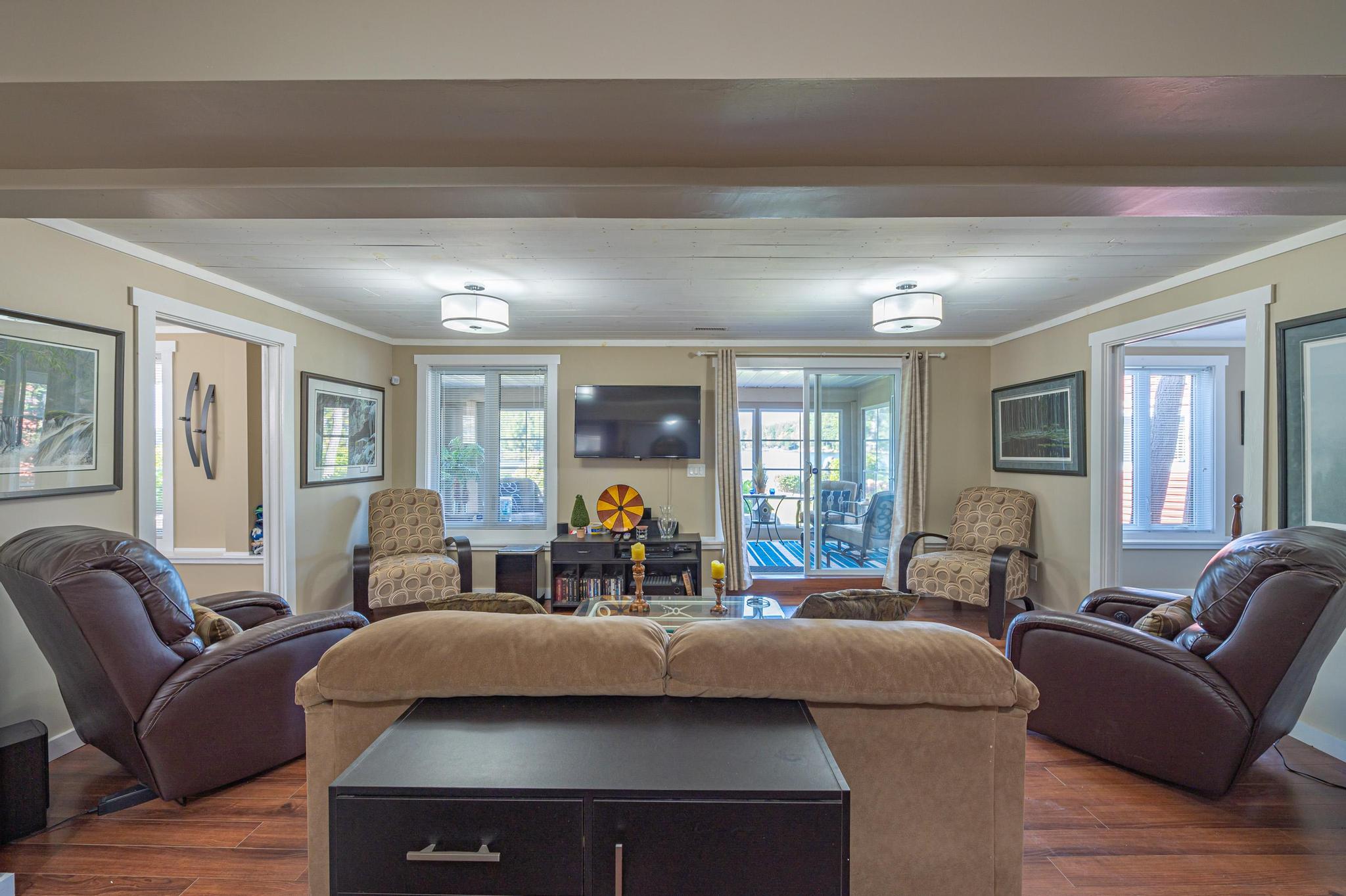 A stylish entertainment room with large windows and comfortable seating.