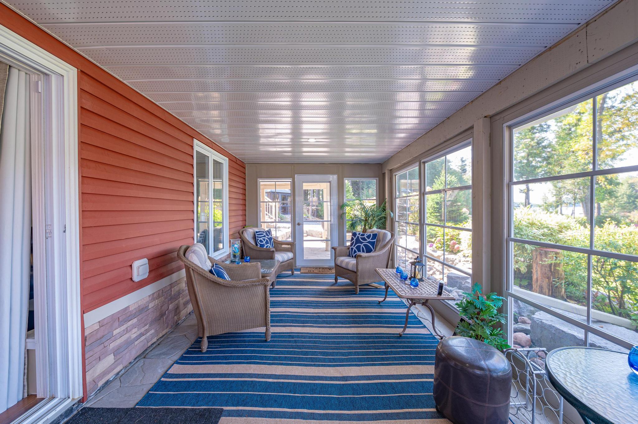 A spacious screened porch with comfortable seating, overlooking the outdoor landscape.
