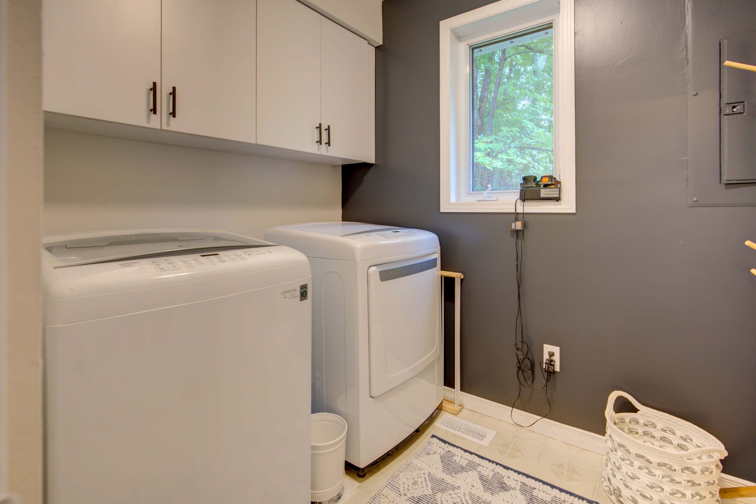 White laundry machines beside each other in a small grey room