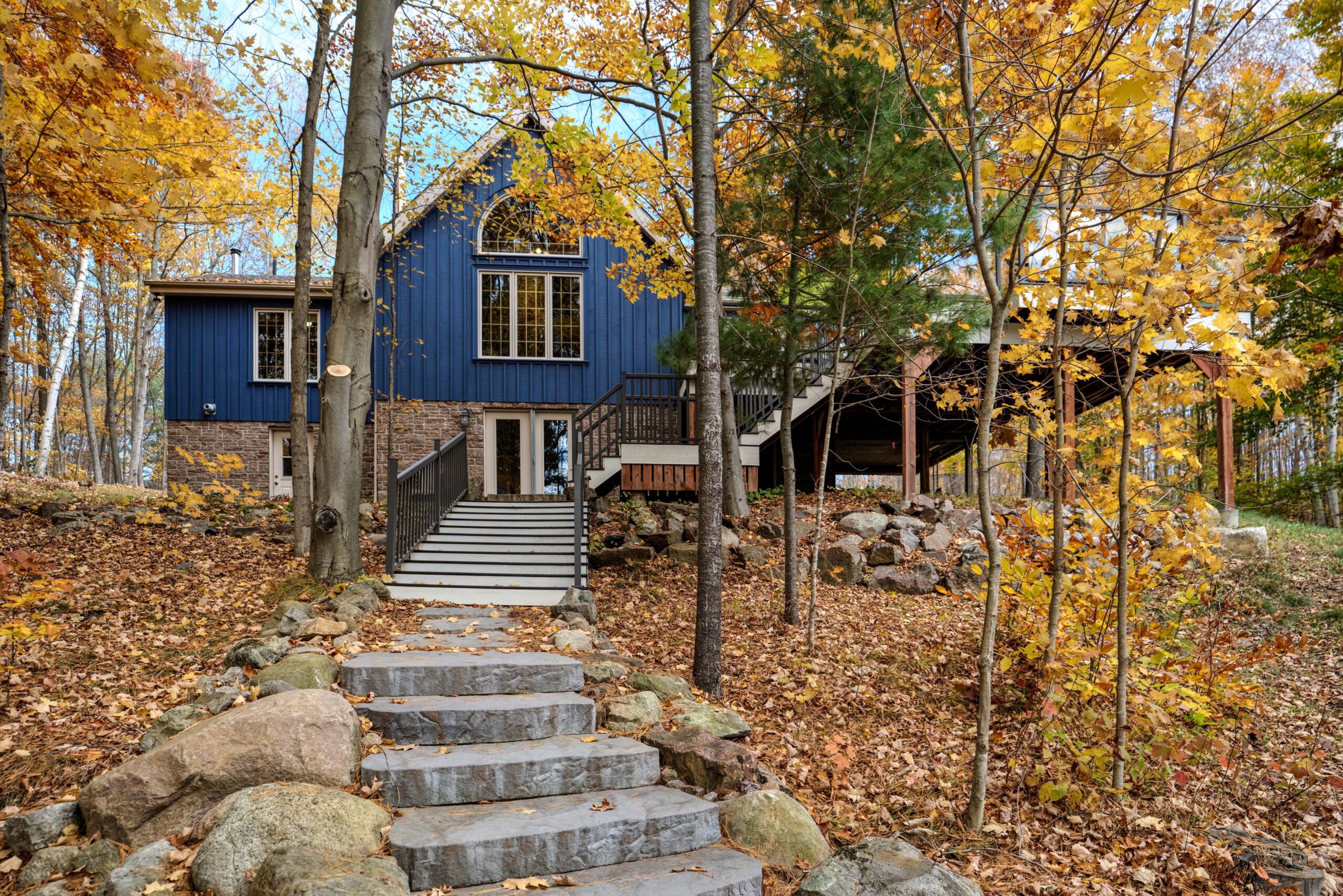 A blue cottage with stone steps in an autumn forest