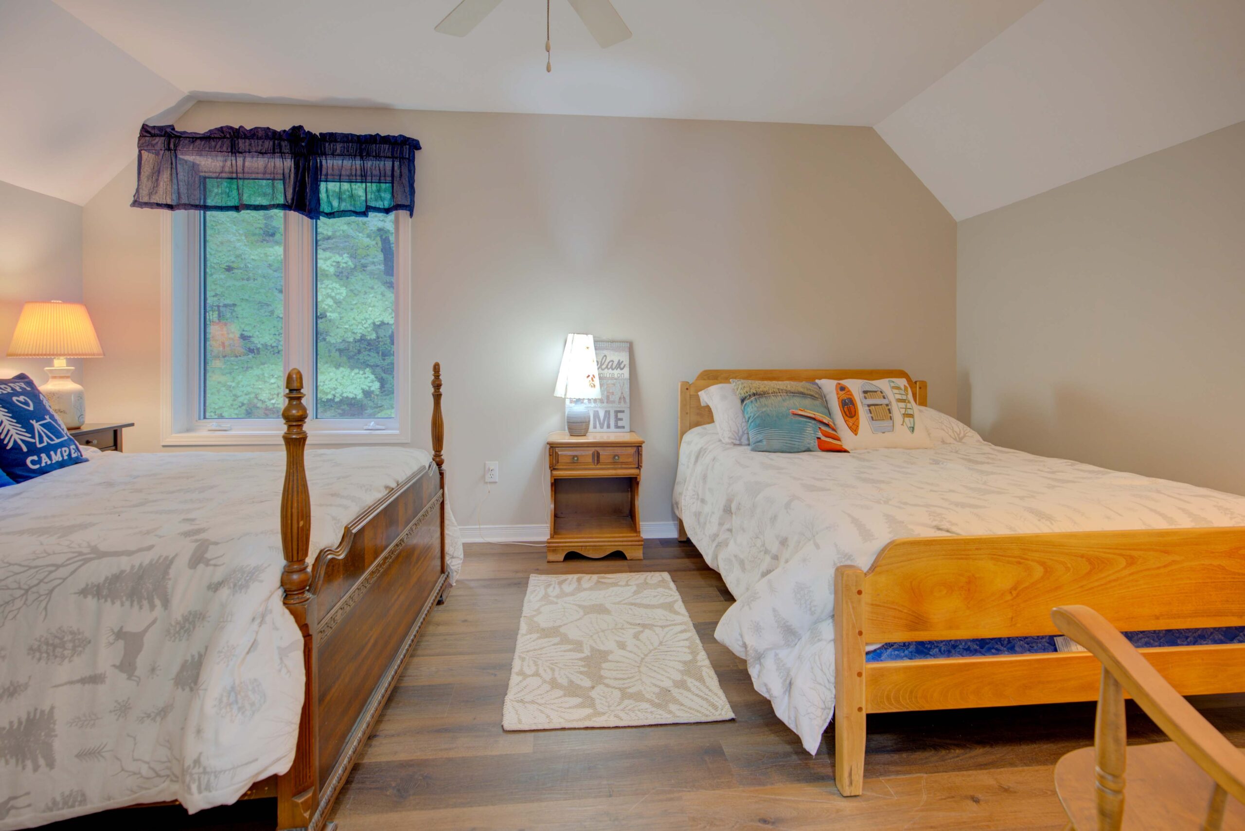 A white bed on a large wood bed frame faces another wood bed