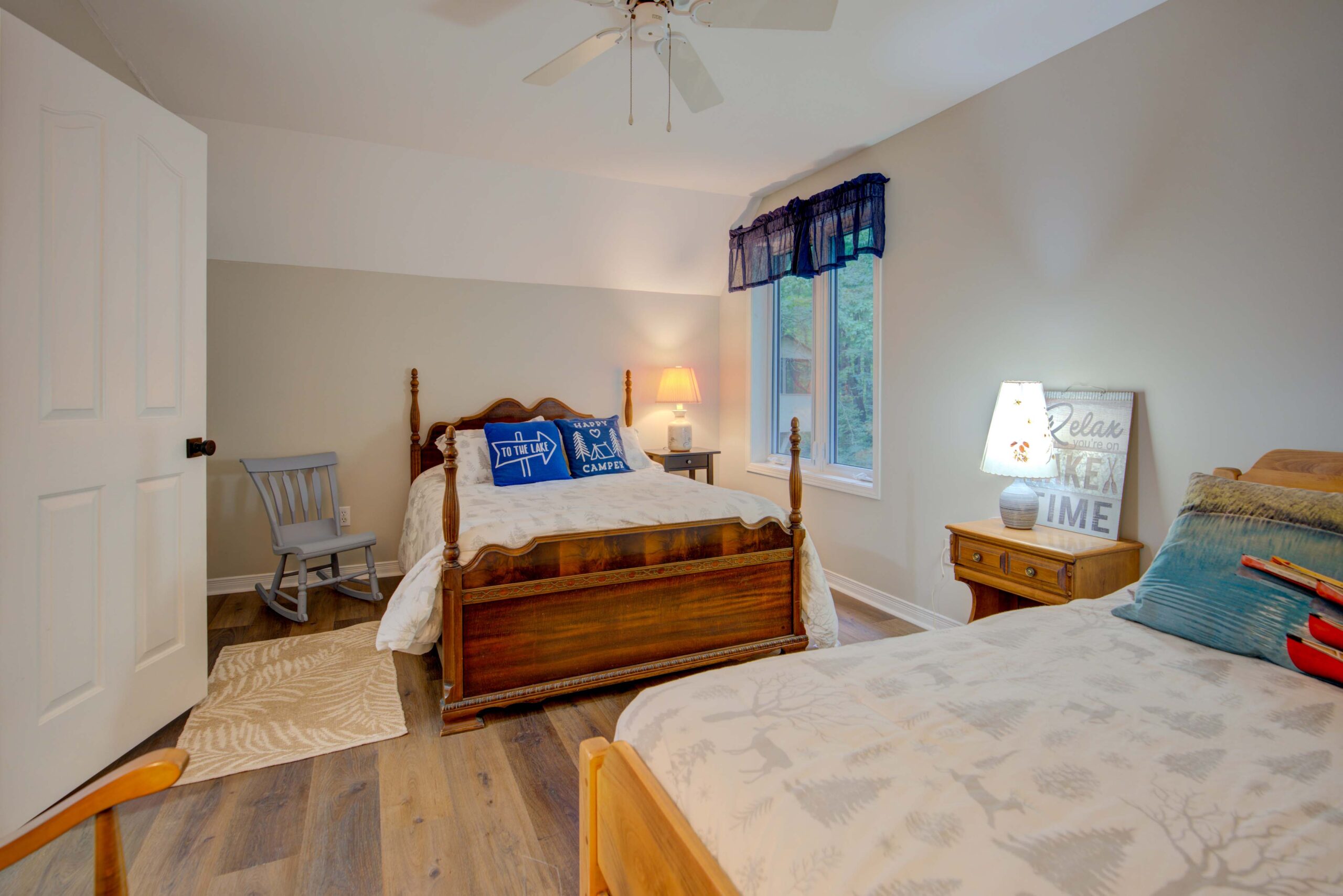 A white bed on a large wood bed frame faces another wood bed